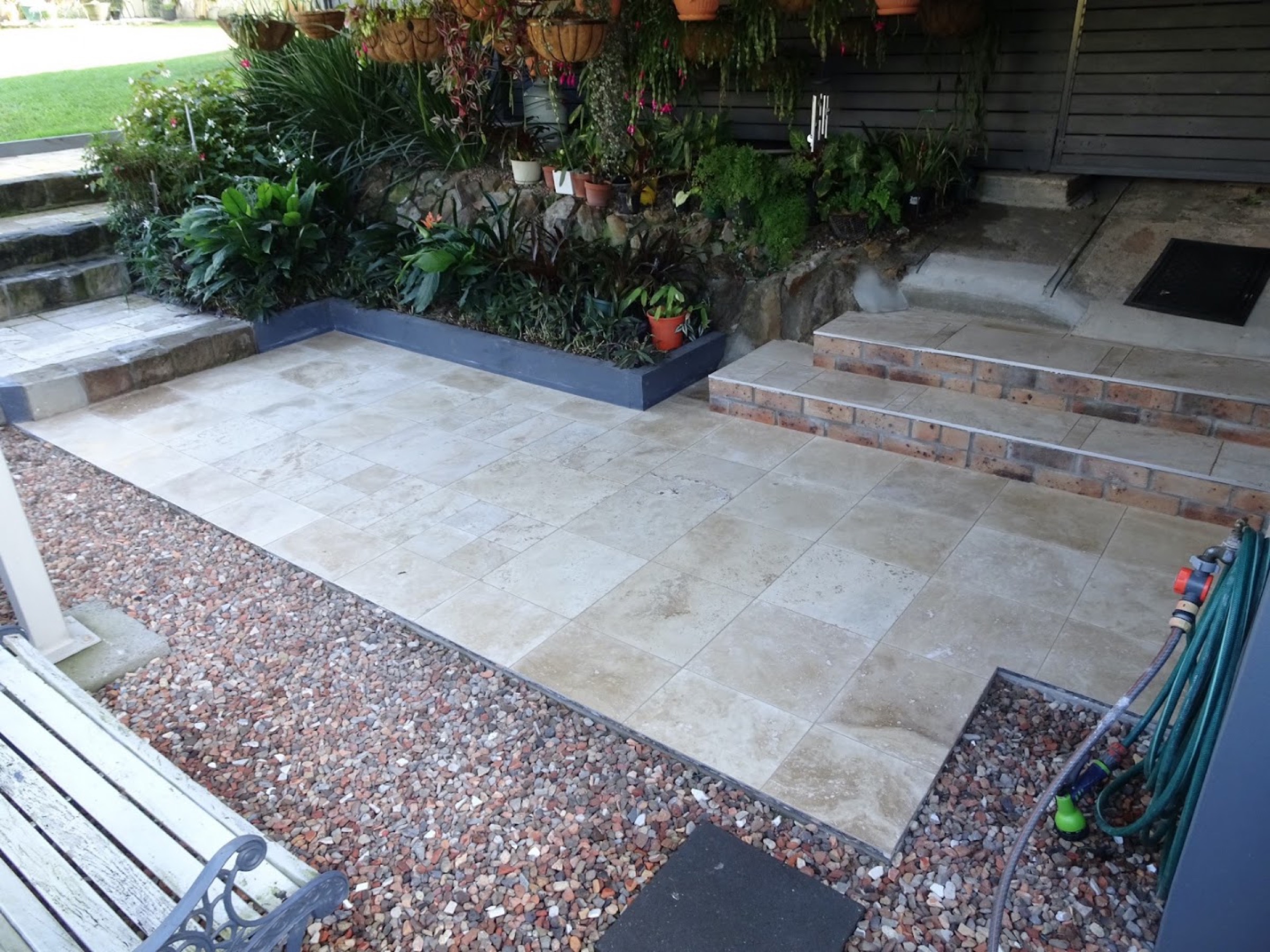 Travertine steps and paving beside a brick house