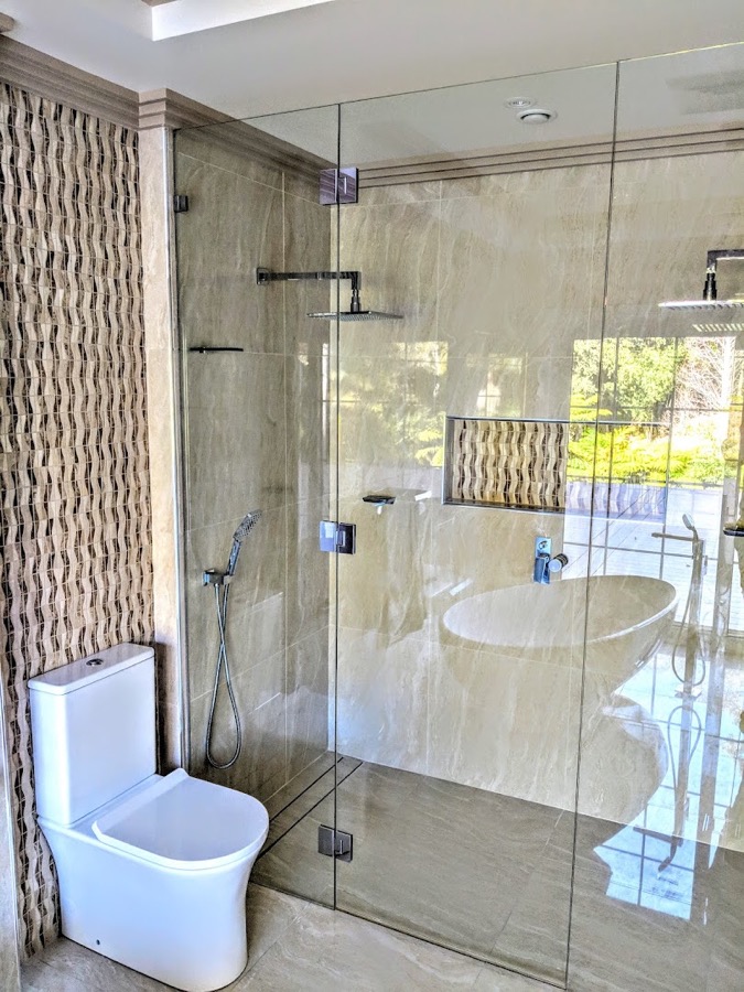 A tiled shower recess with shampoo bottles on the shelf
