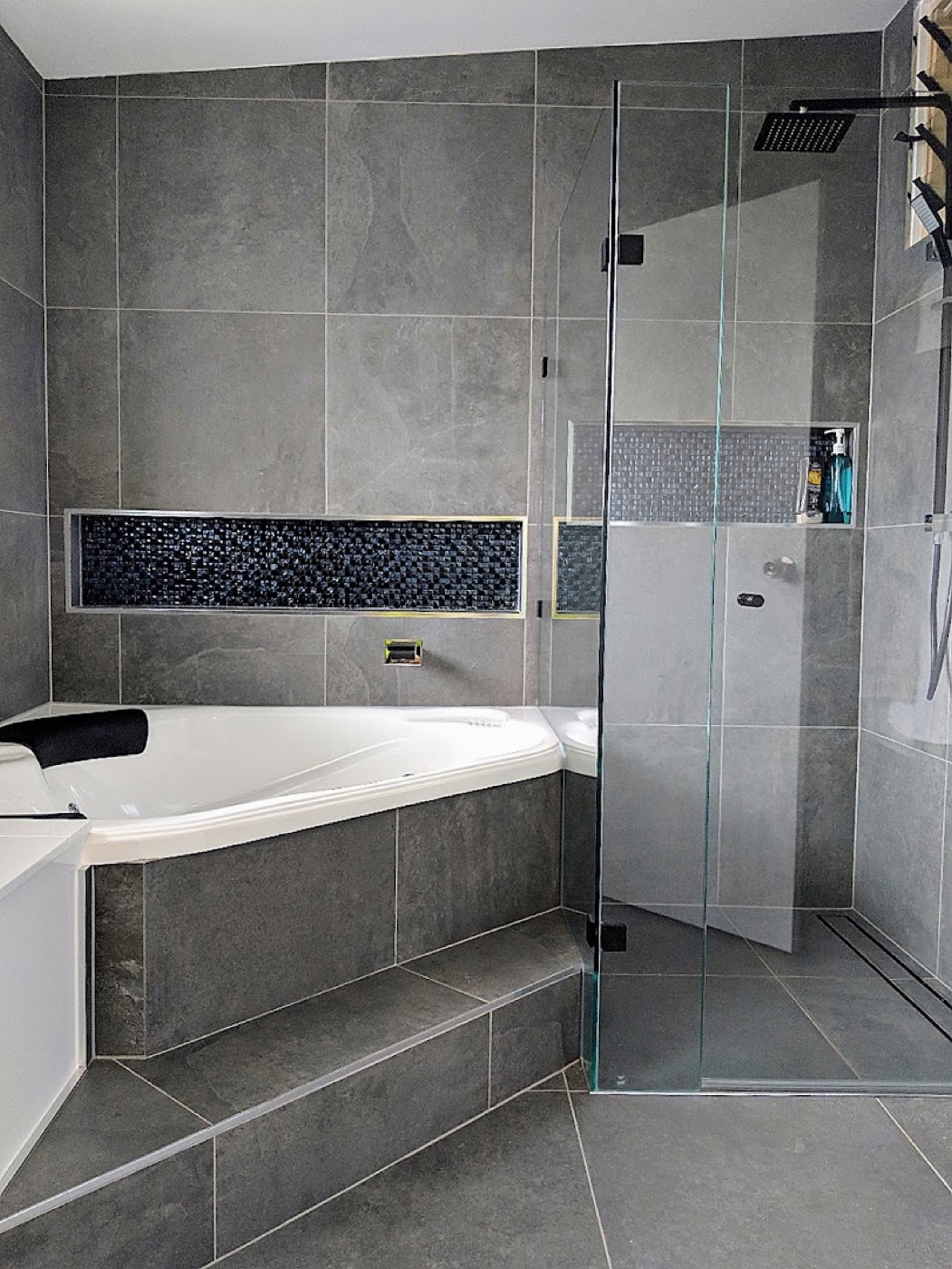 A tiled bath surround with a mosaic inset border