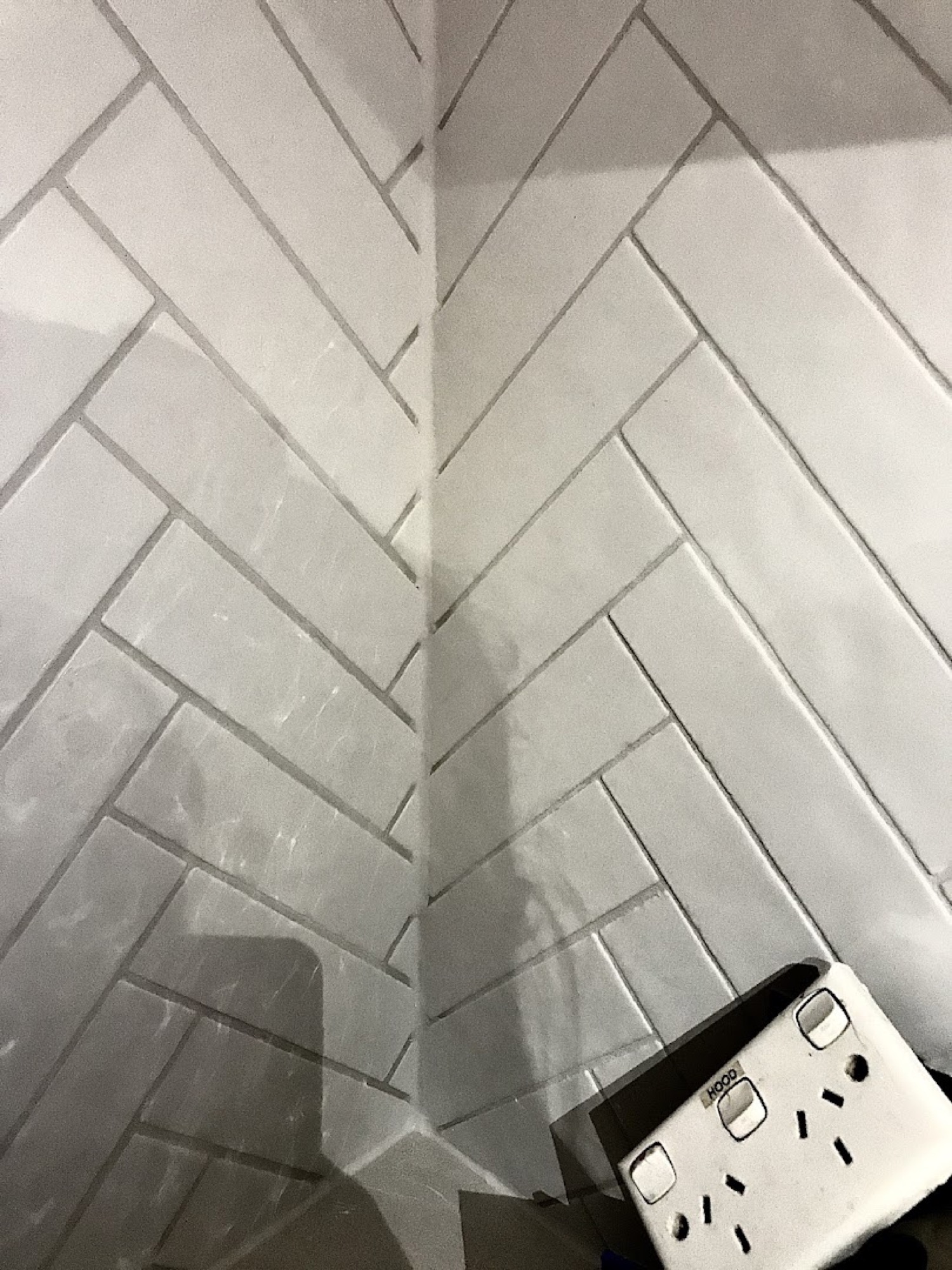 A white herringbone pattern tiled corner beside a power point