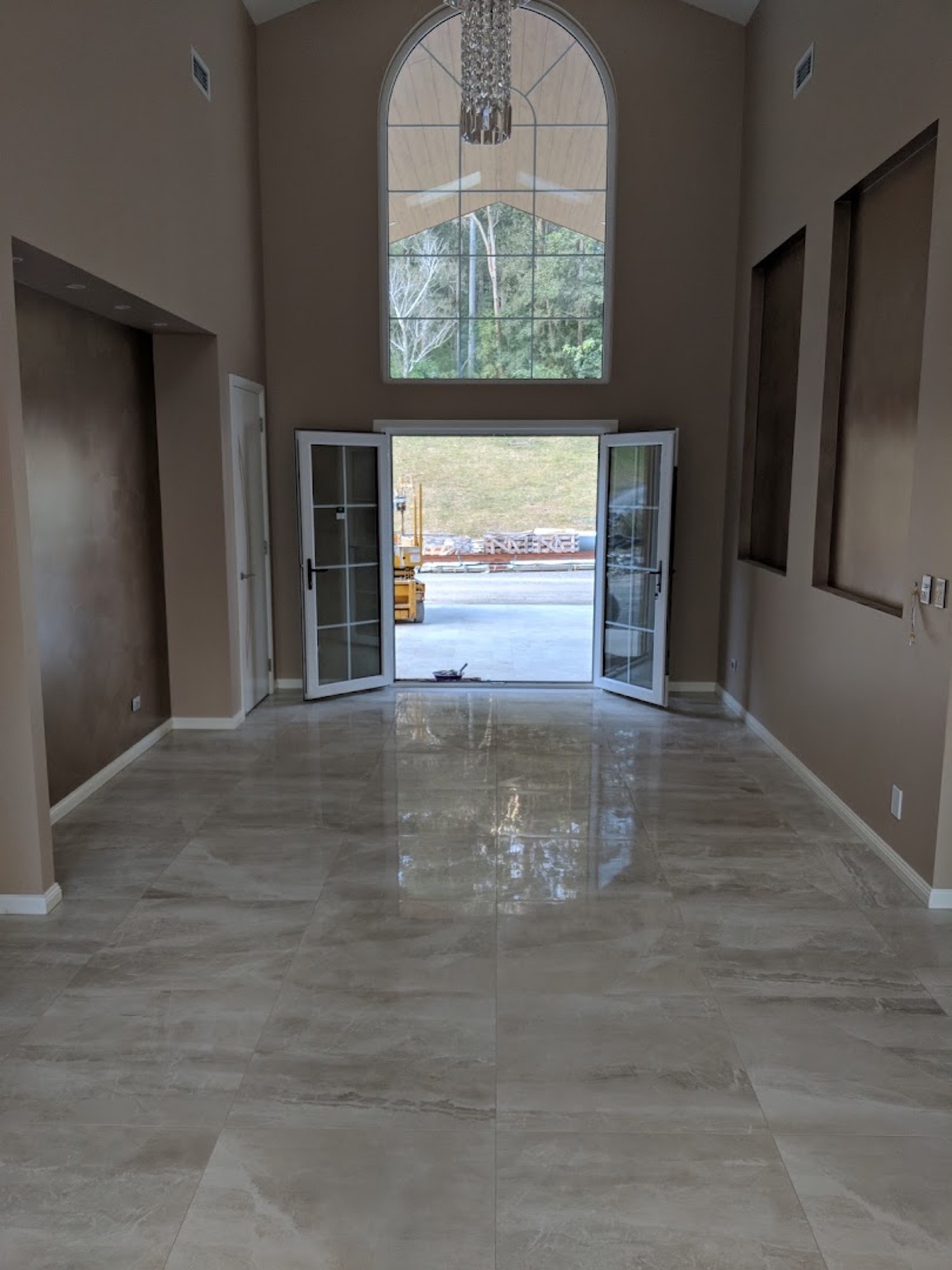 A bright tiled hallway leading to glass doors and an outdoor deck