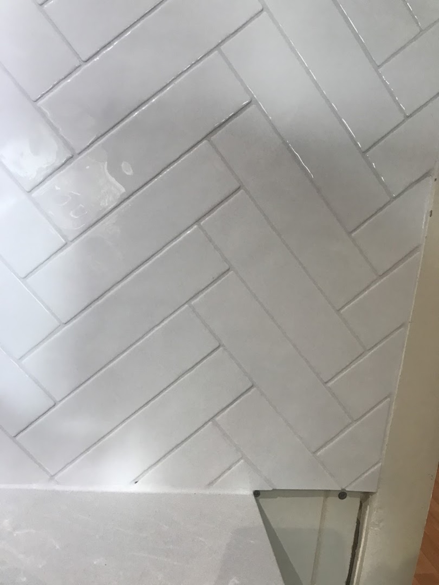 A close-up of a white herringbone pattern tiled bathroom wall