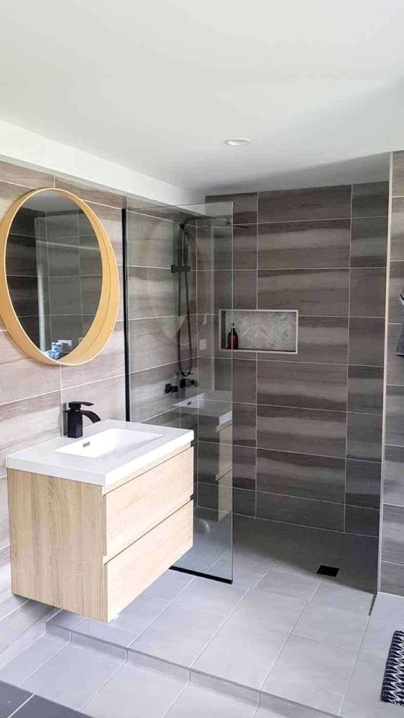 A bathroom vanity with a large mirror set against tiled walls