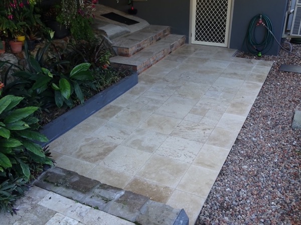 Travertine steps and paving leading through a garden bed