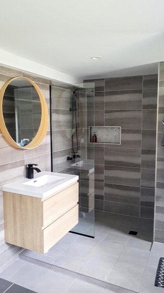 A bathroom vanity with a round mirror set against tiled walls