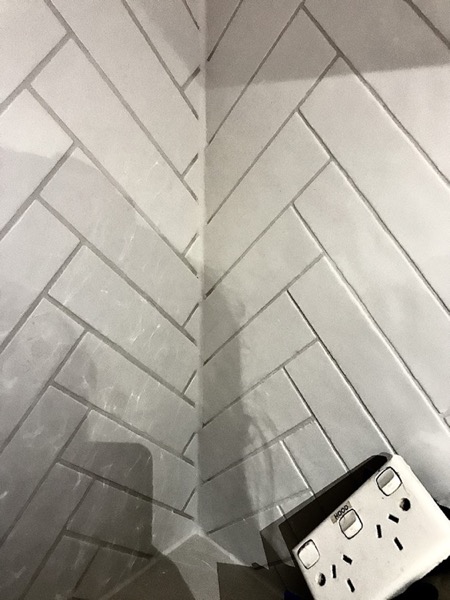 A white herringbone pattern tiled corner beside a power point