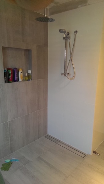 A tiled shower recess with a rain shower head, a second angle