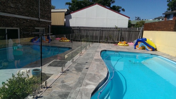Travertine paving around a backyard pool with pool toys on the deck