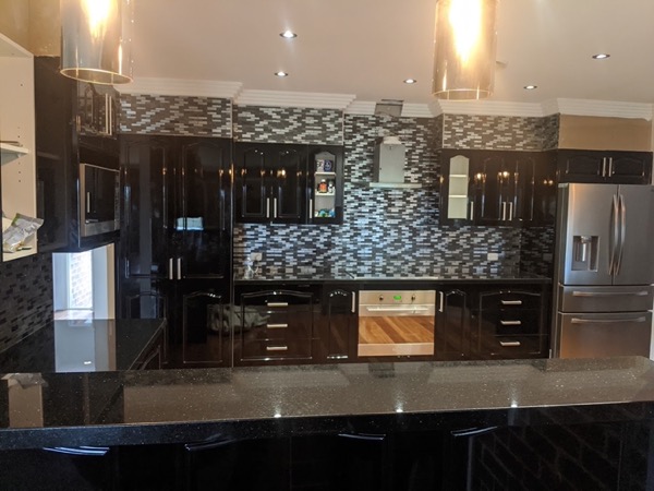 A dark kitchen with a herringbone tile splashback, a second angle