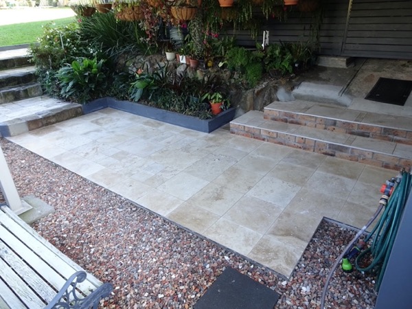 Travertine steps and paving beside a brick house