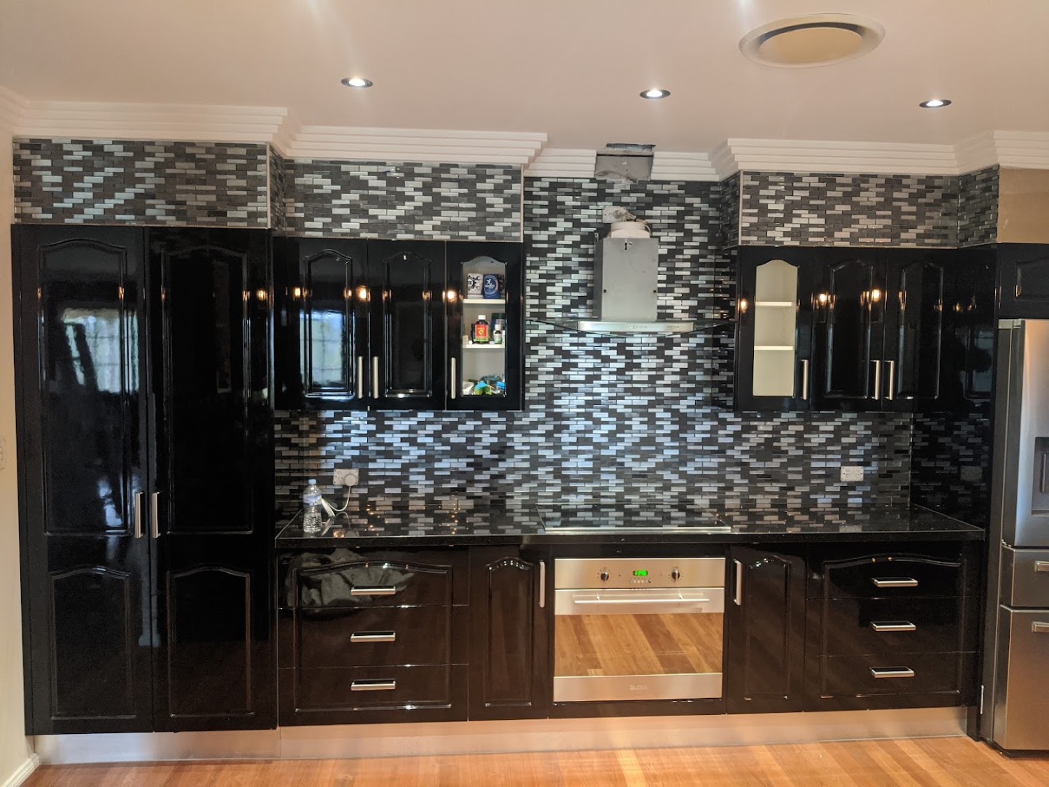 A dark kitchen with a herringbone tile splashback